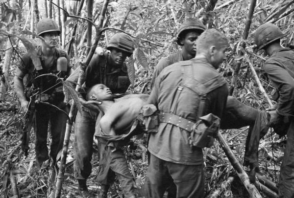 Soldiers of the 101st Airborne Division carry a wounded buddy through the jungle in May 1966. (AP Photo/Henri Huet)